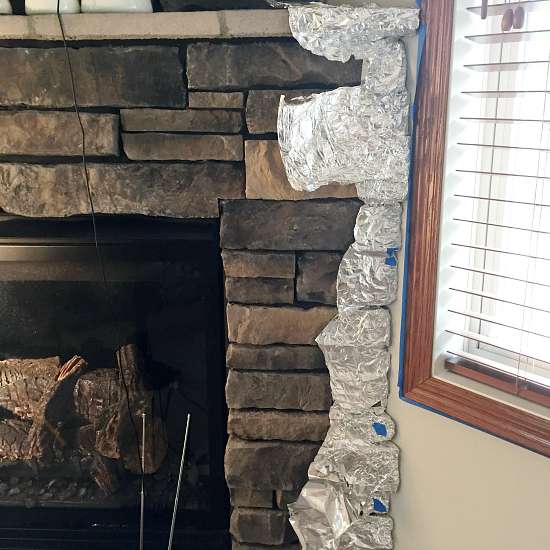 Edge of stone fireplace wrapped with aluminum foil in order to paint the walls