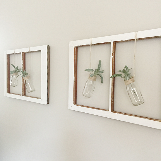 Farmhouse wall decor using two old chippy white window hung on the wall with milk jars and faux greenery