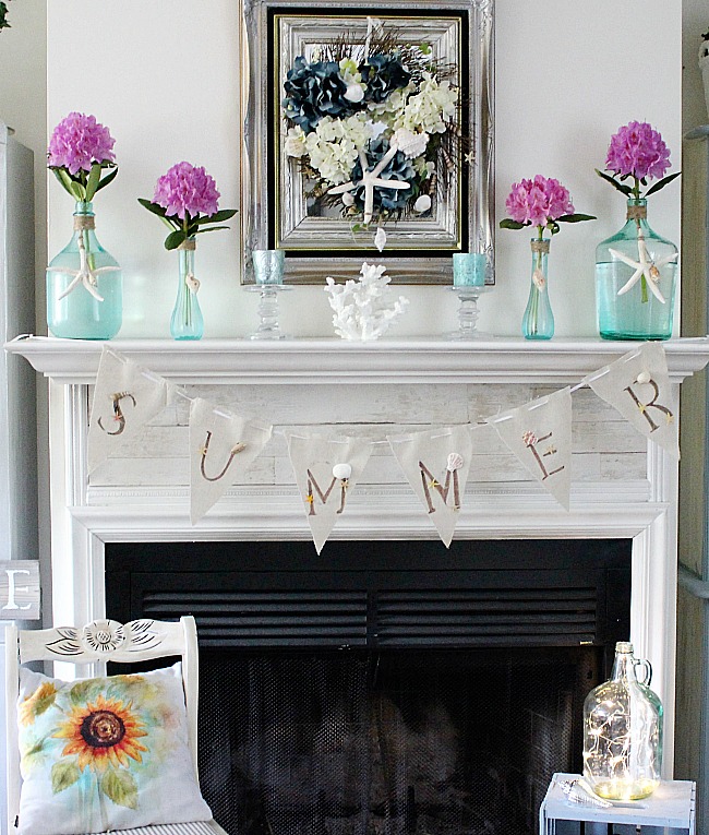 Summer mantel featuring blue glass vases and bright pink flowers