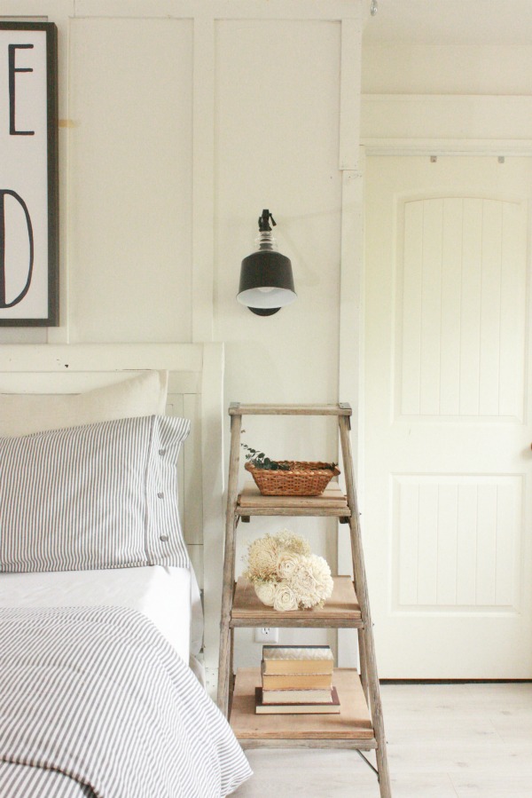 Wooden ladder acting as nightstand in farmhouse style bedroom