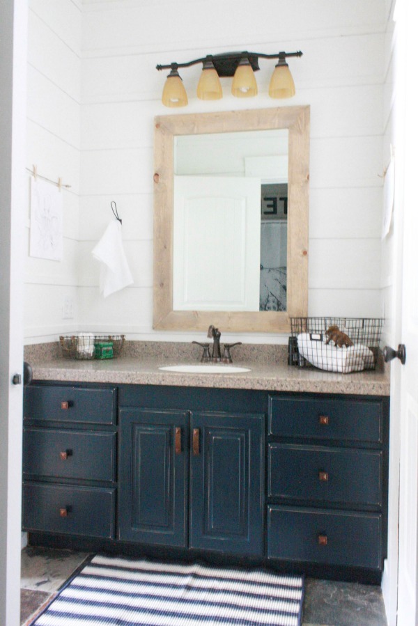 $100 bathroom makeover featuring a faux shiplap wall and navy vanity