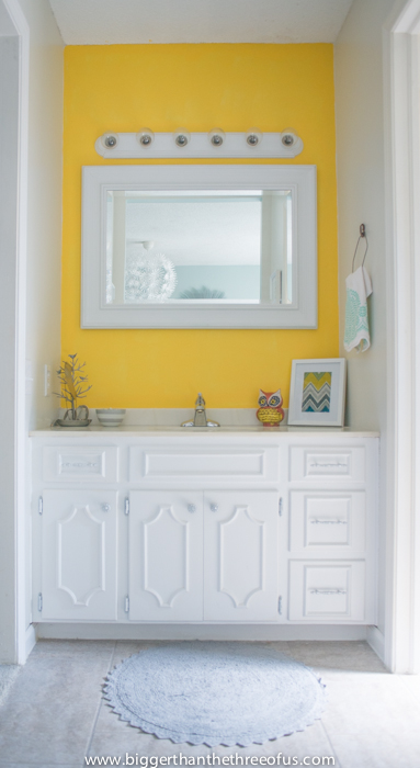 Before image of a bathroom about to get a $100 makeover. Bright yellow walls with a white vanity.