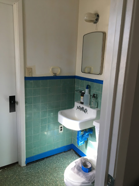 Bathroom prior to $100 makeover showing green tiled wall and green flooring