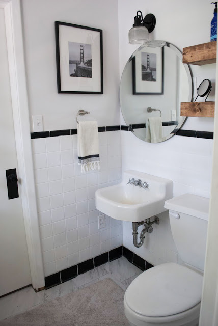 $100 bathroom makeover featuring black and white tile on wall with new flooring and freshly painted walls