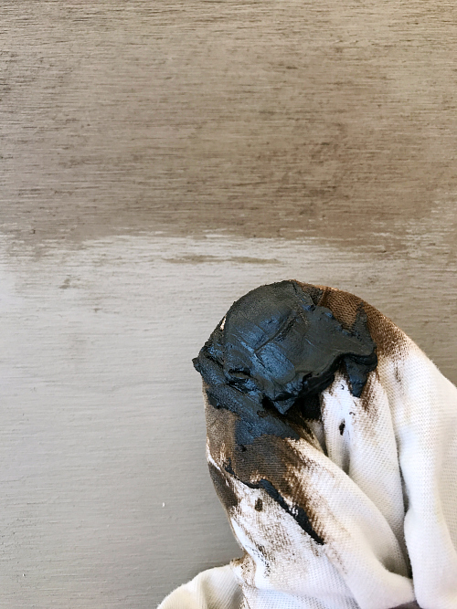 Dark wax on a lint-free cloth being applied over chalk paint