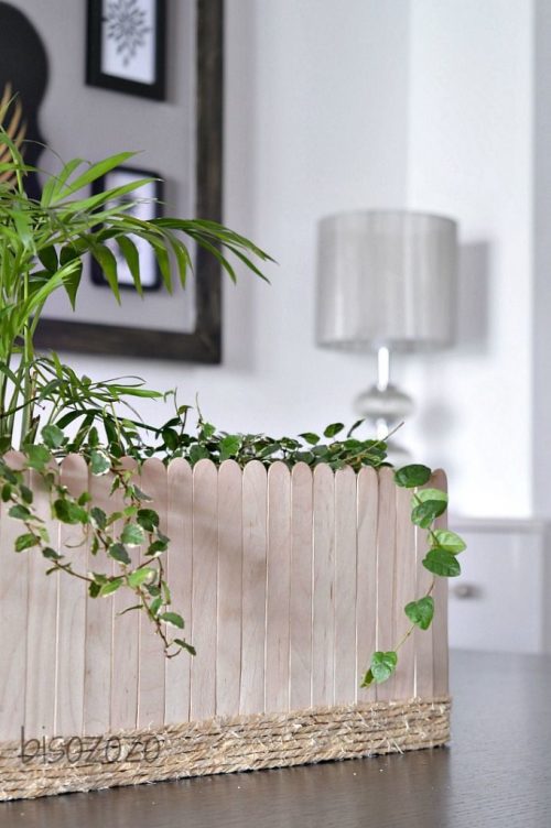 A box covered with vertical popsicle sticks used as a planter