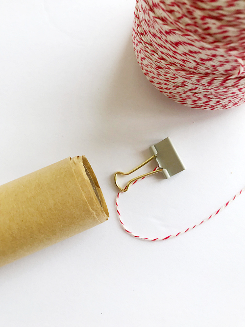 Binder clip on end of baker's twine to weight it down to create hanger for DIY scroll