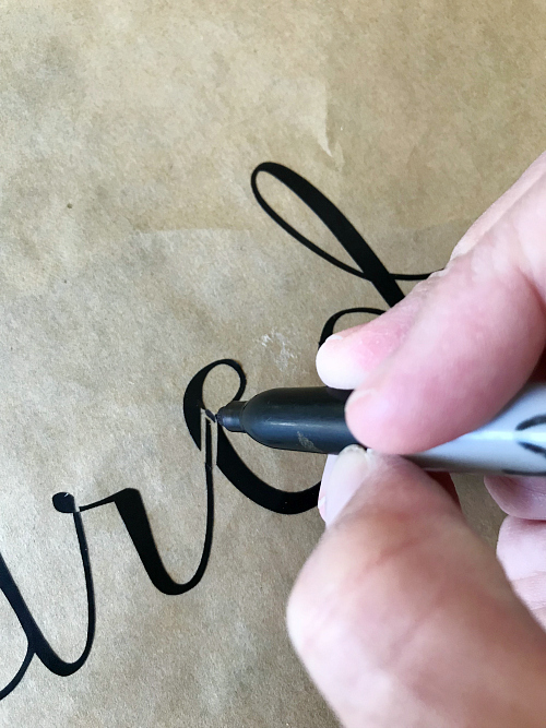 Black permanent marker coloring in gaps of letters