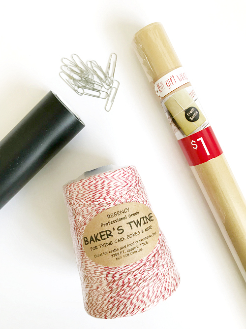 Items needed to make a DIY Christams Scroll: Kraft paper, vinyl, paperclips, and baker's twine