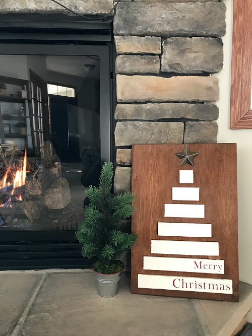 Reversible sign with a scrap wood Christmas tree next to a small faux Christmas tree