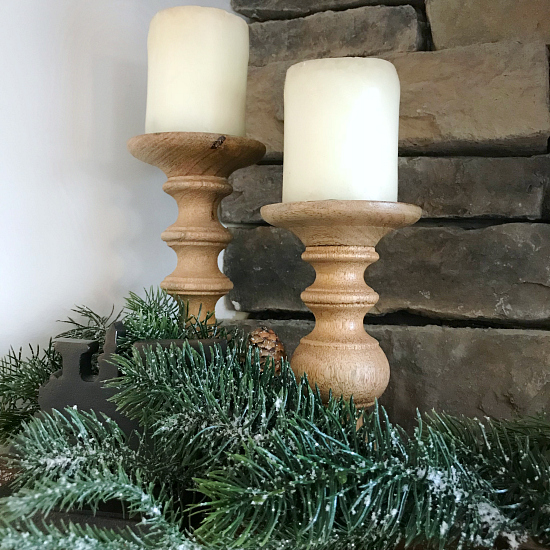 Wood candlesticks displayed with greenery on a mantel