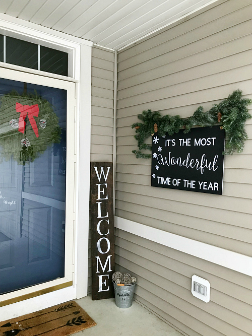 Budget friendly Christmas porch showing a Christmas sign made from black foam board