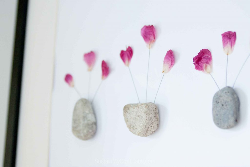 Framed pressed flowers with rocks used as vases