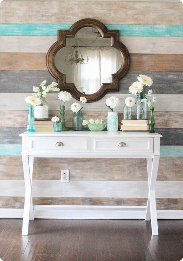 Blue masons jars and vases hold white flowers on entry table