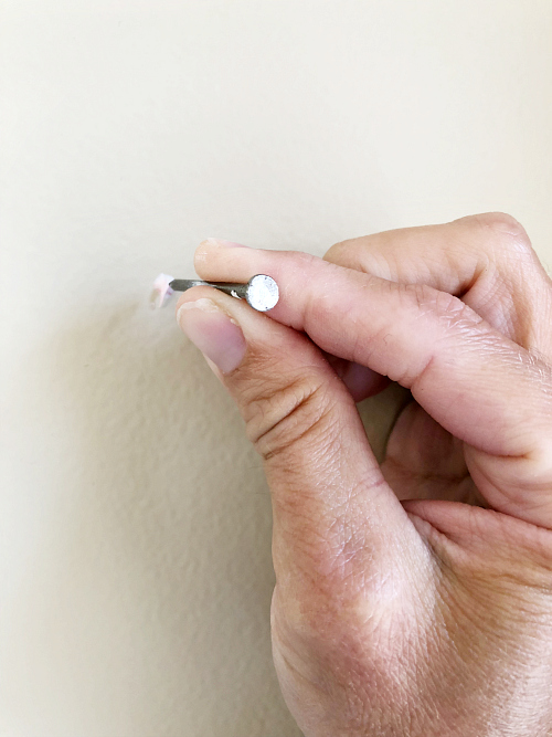 Pounding nail into wall where toothpaste mark was left