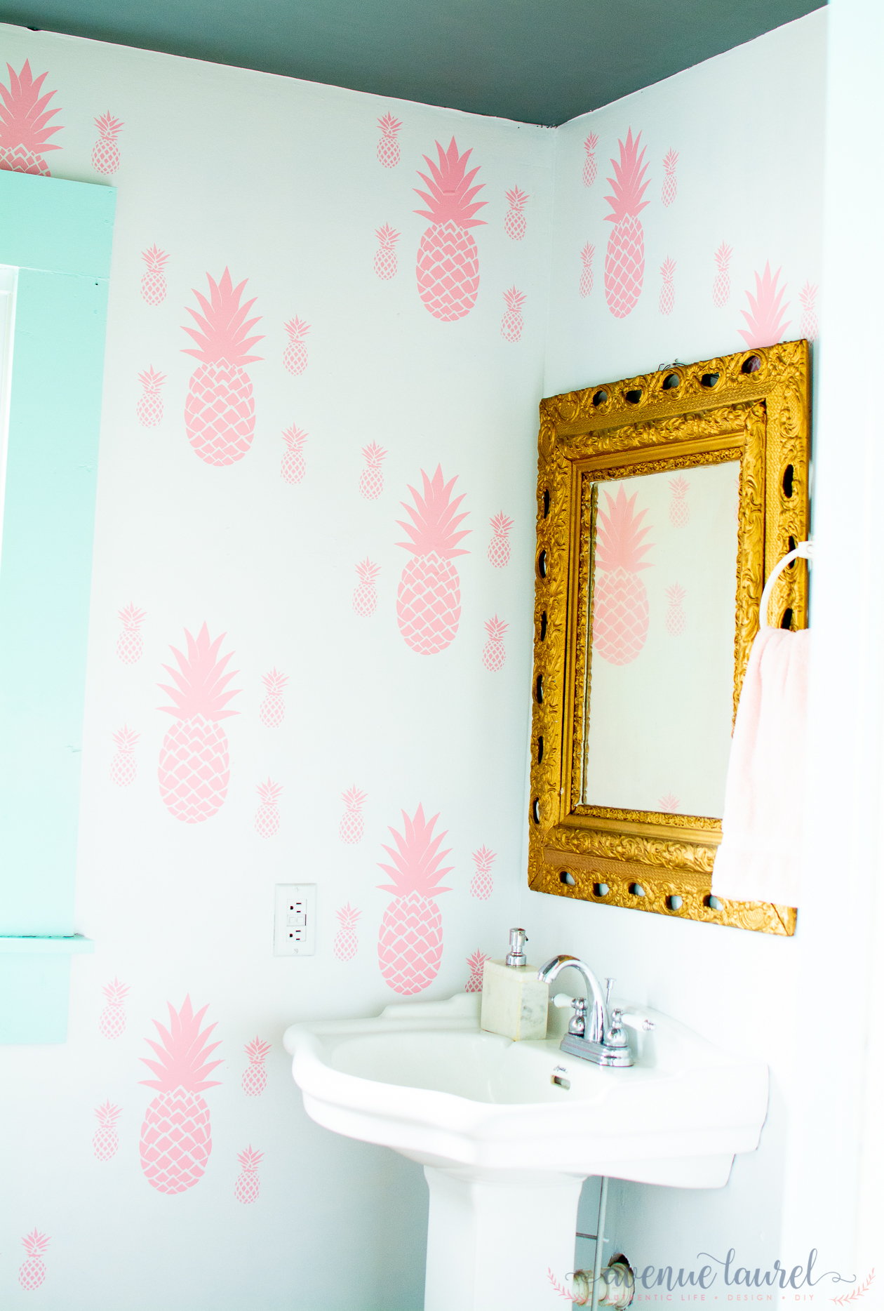 Powder room after $100 makeover. Pink stenciled pineapples on the wall with aqua trim