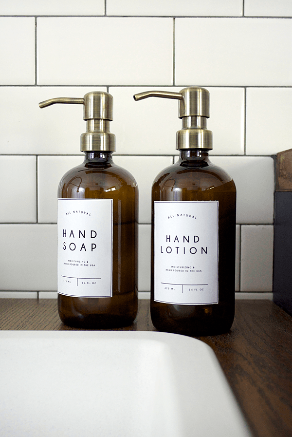 Amber glass dispensers labeled hand soap and hand lotion.