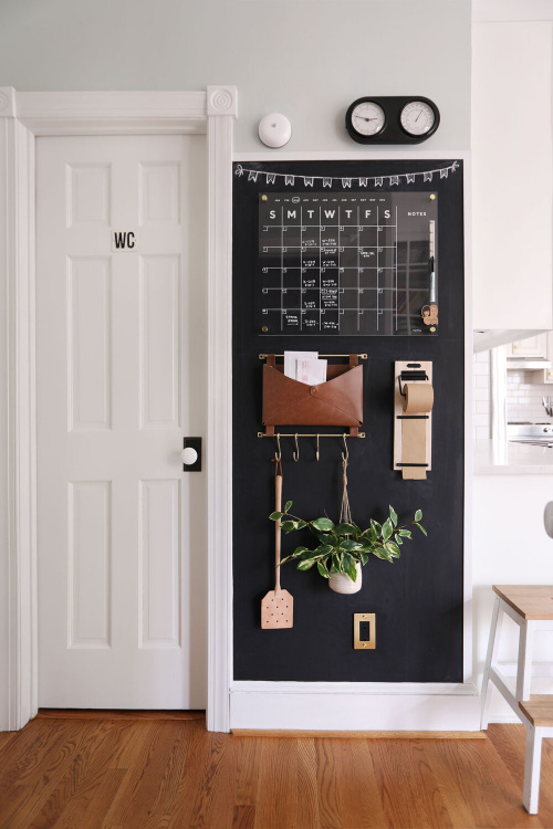 Command Center on a black wall with calendar, shopping list, and leather pouch.