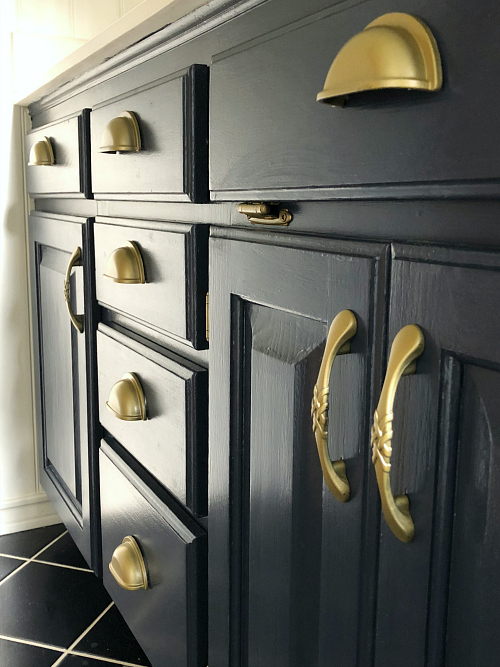 Up close view of vanity painted with navy latex paint and hardware spray painted in brass