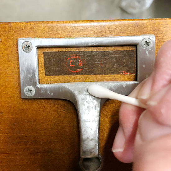 Cleaning card catalog hardware with cotton swab and rubbing alcohol
