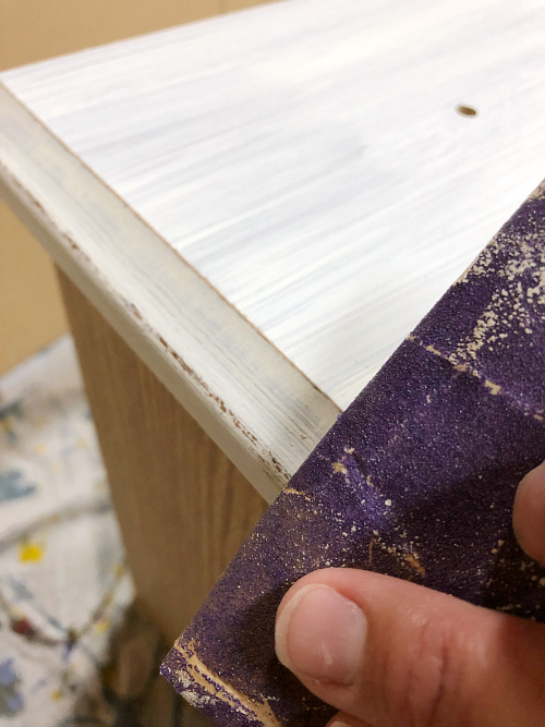 Sanding area of dresser where beeswax was applied to create a distressed appearance