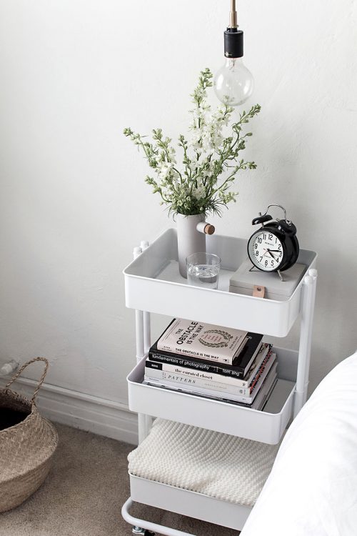 Three tiered metal cart being used as a nightstand