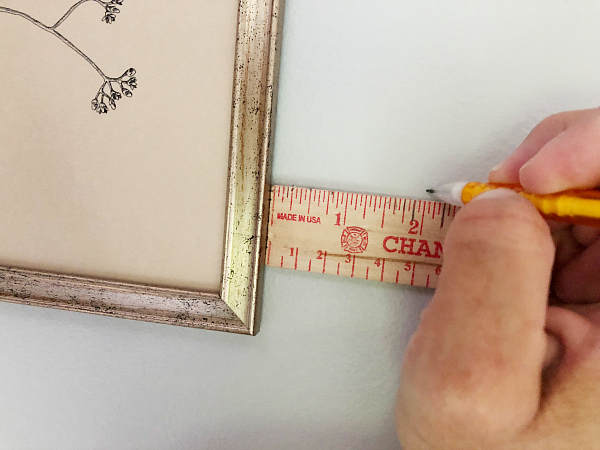 Using a ruler to make sure frames are evening spaced in this farmhouse gallery wall