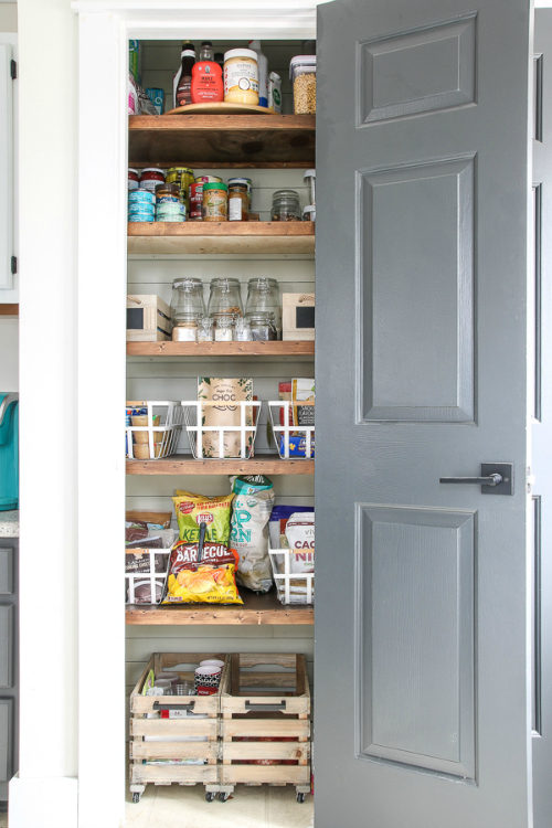 $100 Pantry makeover with newly installed wood shelves, and food items organized in containers and crates.