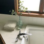 $100 Bathroom Makeover showing view of tub with folded towels and eucalytus