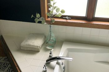 $100 Bathroom Makeover showing view of tub with folded towels and eucalytus