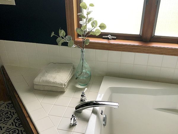 $100 Bathroom Makeover showing view of tub with folded towels and eucalytus