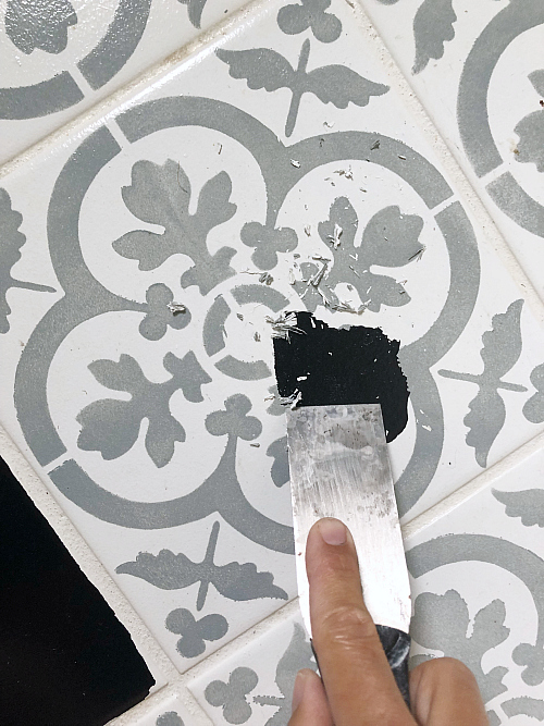 Fixing peeling paint on painted tile floor. Using a putty knife to scrape off peeling paint