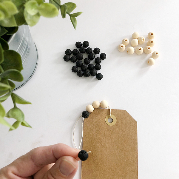 Adding wood and lava beads to cording to make a bookmark