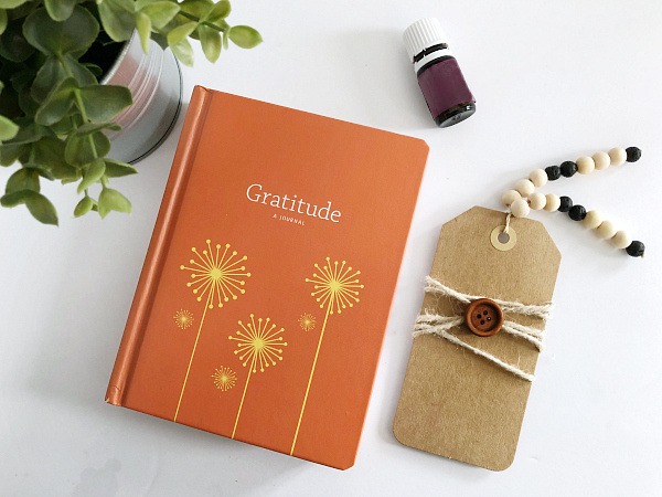 DIY Diffuser bookmark next to a Gratitude journal and bottle of essential oil
