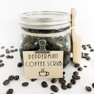 Homemade Peppermint Coffee Scrub in a glass jar with a wooden scoop and label attached with a clip