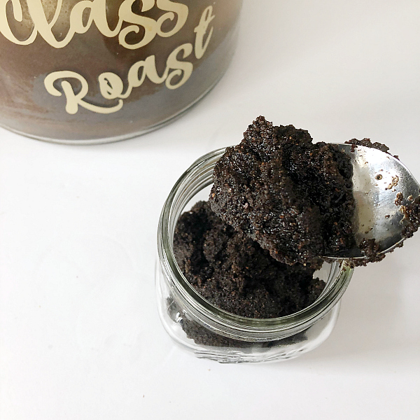 Scooping peppermint coffee scrub into a glass jar