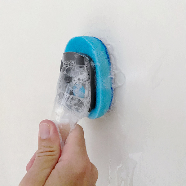 Using dish brush to clean shower with DIY Shower Cleaner