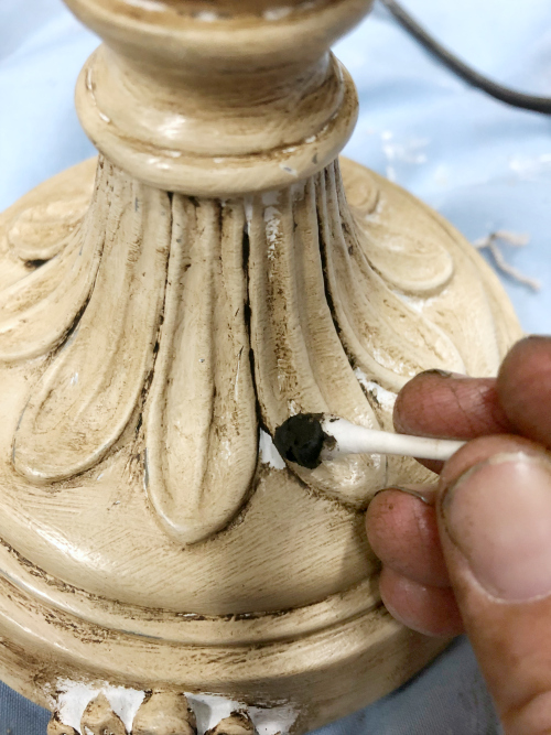 Using cotton swab to apply wax to nooks and crannies of lamp base