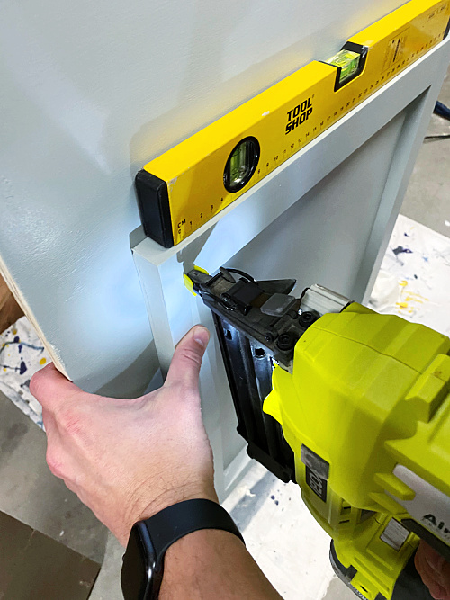 Using a nail gun to attach door to faux vanity made to hide a utility sink