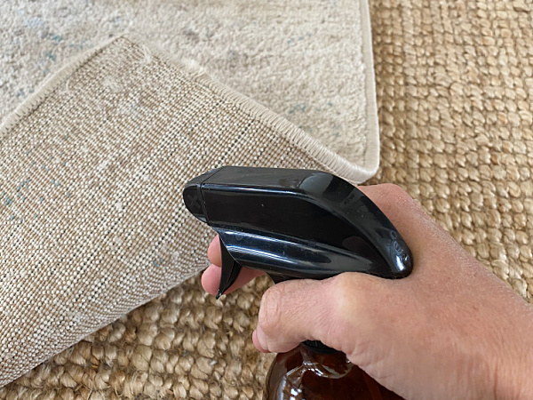 Spraying water on underside of rug to flatten curling corner