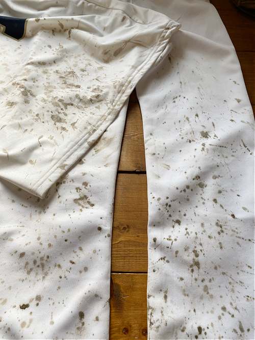 A white baseball uniform covered in mud splatters