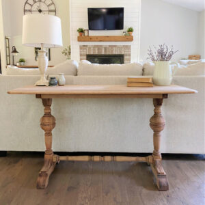 Farmhouse style table that has been stripped with oven cleaner placed behind couch in living room