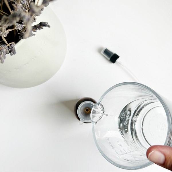 Pouring room spray into glass spray bottle