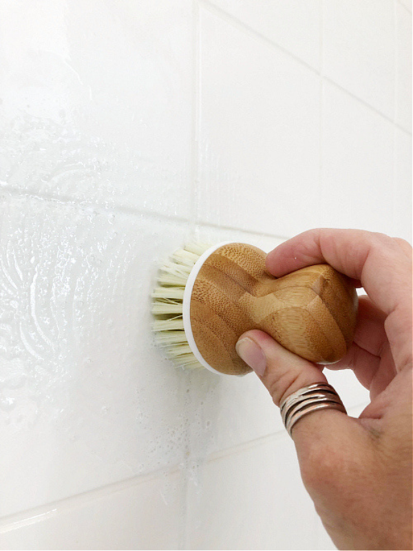 Scrubbing shower wall with dish brush