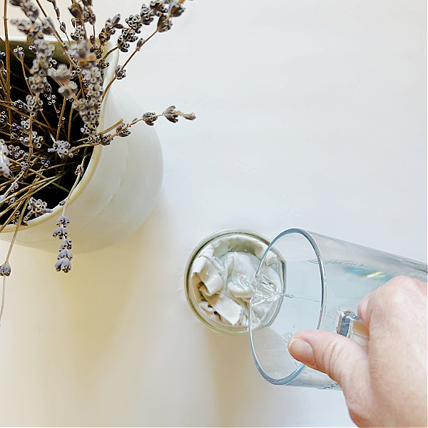 Pouring cleaning solution over cloth pieces to make DIY Wipes