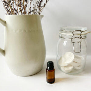 DIY Shower Steamers in Jar next to bottle of essential oil and vase of lavender
