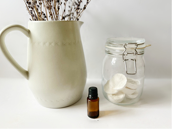 DIY Shower Steamers in Jar next to bottle of essential oil and vase of lavender