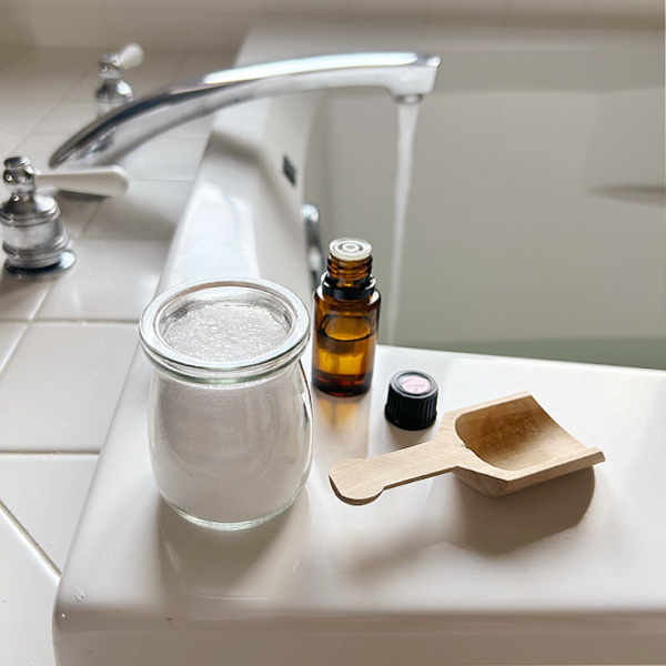 Bath Salts and essential oil sitting on side of bathtub