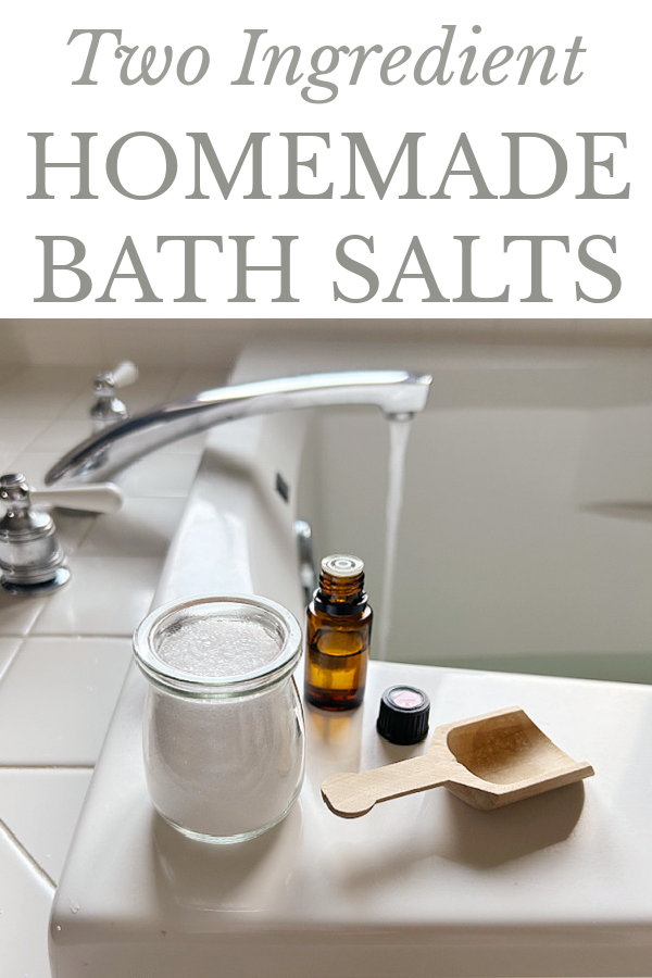 DIY Bath Salts sitting on edge of bathtub along with a bottle of essential oil and a wood scoop