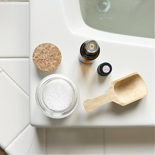 Items needed to make bath salts: Epsom Salt and essential oil with wooden scoop